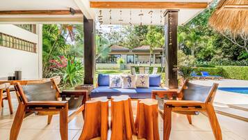 Un área de estar exterior moderna con mobiliario de madera y una piscina.
