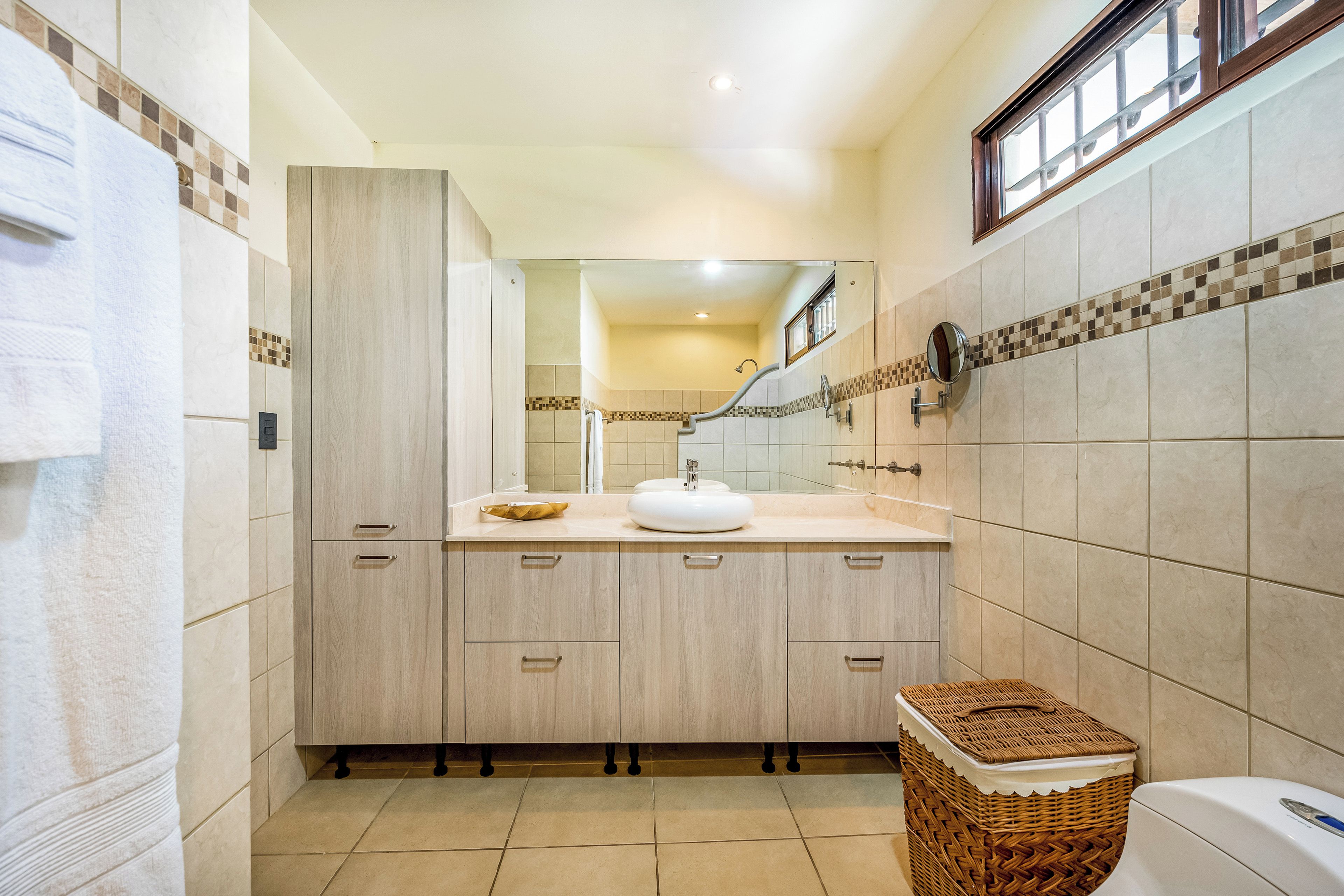 A bathroom with a large mirror, a sink, and a toilet.