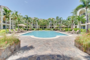 A resort pool area with lounge chairs and palm trees. - Walkable Coco Beach Condo w/ Balcony, Pool (Sardinal)