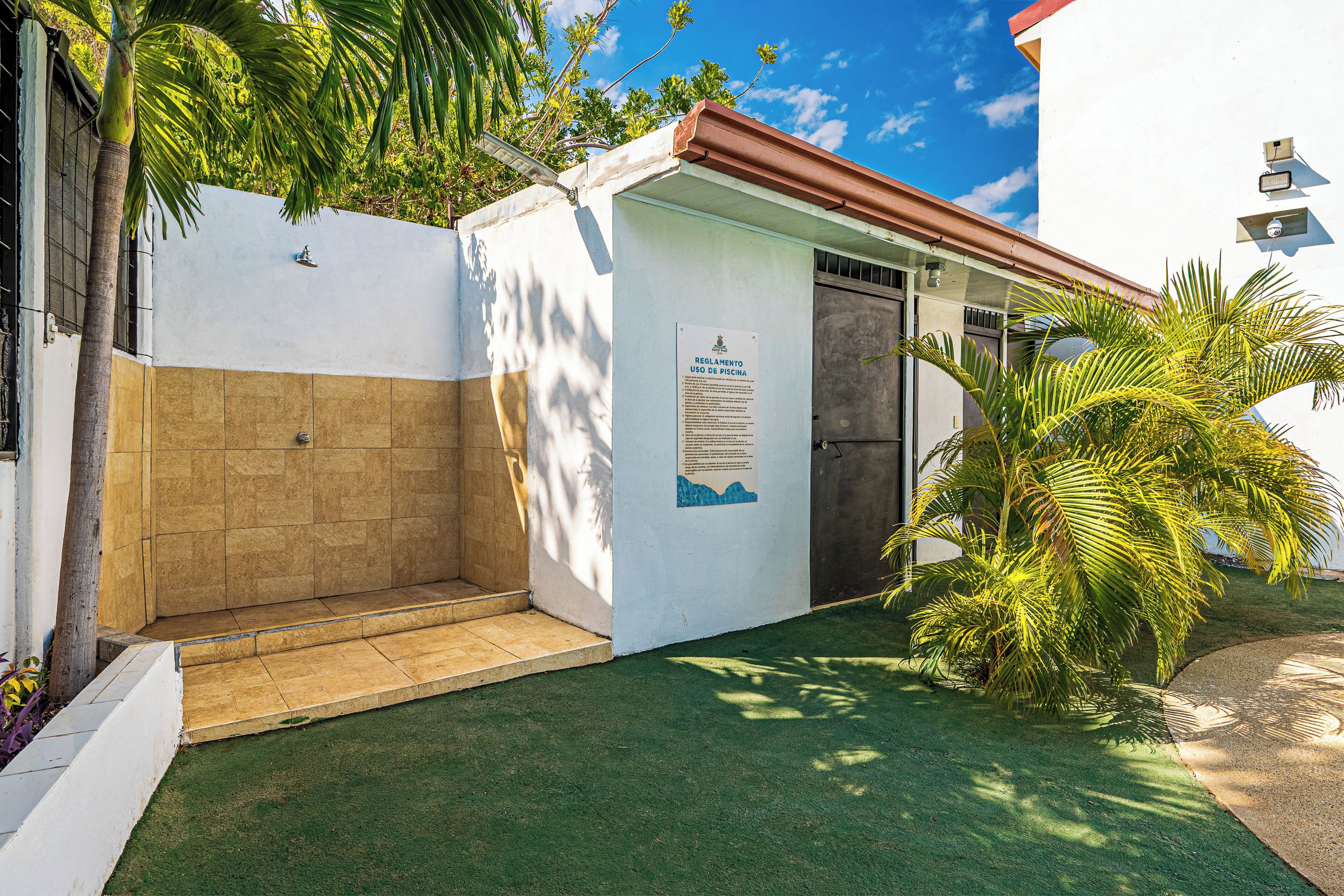 A small building with a door, a poster on the wall, and a palm tree in the foreground.