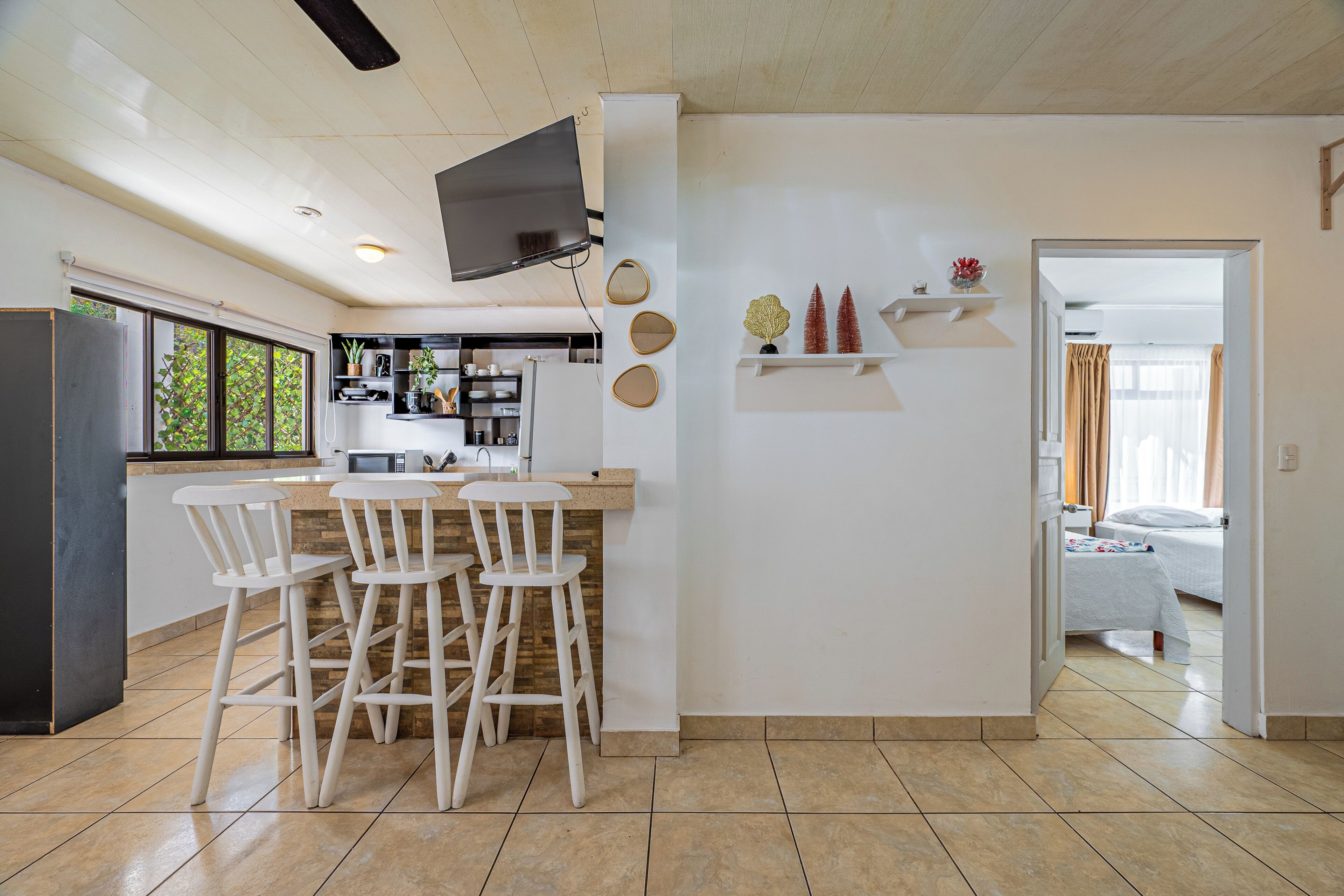 Une cuisine moderne avec un coin repas, un téléviseur fixé au mur et une vue sur le salon attenant.