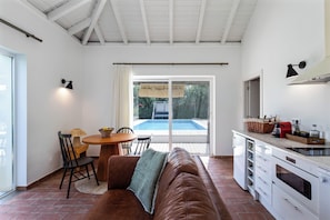 Una cocina moderna con comedor, sofá y vista a una piscina.