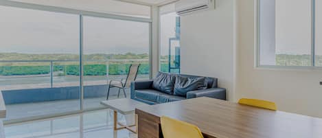 A modern room with a large window, a sofa, a dining table, and chairs.