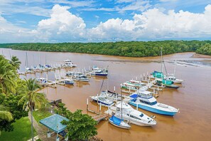A marina with multiple boats docked, surrounded by lush greenery and a clear sky. - Ocean Views in El Roble: Pool & Gym Access! (Puntarenas)