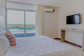A hotel room with a bed, a television, and a view of a body of water. - Ocean Views in El Roble: Pool & Gym Access! (Puntarenas)