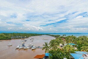 A coastal marina with boats, a bridge in the distance, and lush greenery. - Ocean Views in El Roble: Pool & Gym Access! (Puntarenas)