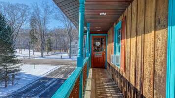 A covered outdoor corridor with a wooden floor, wooden walls, and a blue railing.