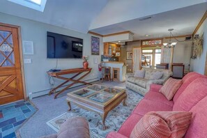 A living room with a sofa, a coffee table, and a television.