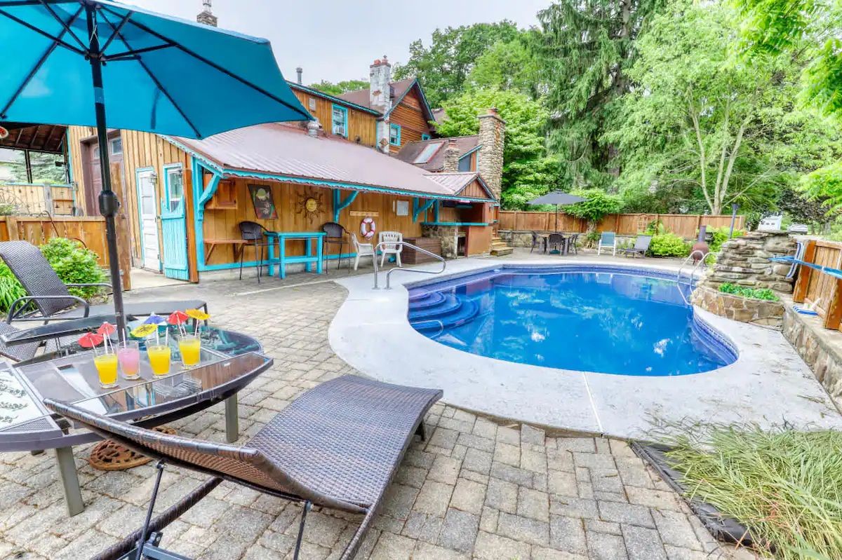 Un jardin avec une piscine, un espace salon extérieur et une maison en bois.