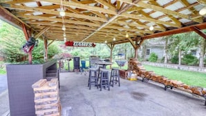 An outdoor patio with a covered seating area, a grill, and a sign that reads 'GAMES'. - Large Ski Home: Seasonal Pool & Year-round Hot Tub (Ellicottville)
