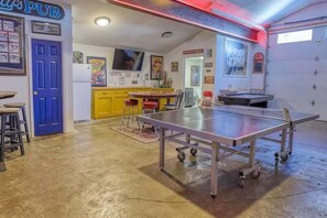 A room with a ping pong table, a blue door, and a yellow cabinet. - Large Ski Home: Seasonal Pool & Year-round Hot Tub (Ellicottville)