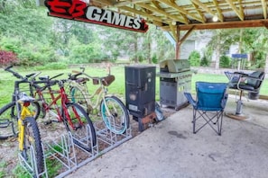 A covered outdoor area with a grill, chairs, and bicycles.