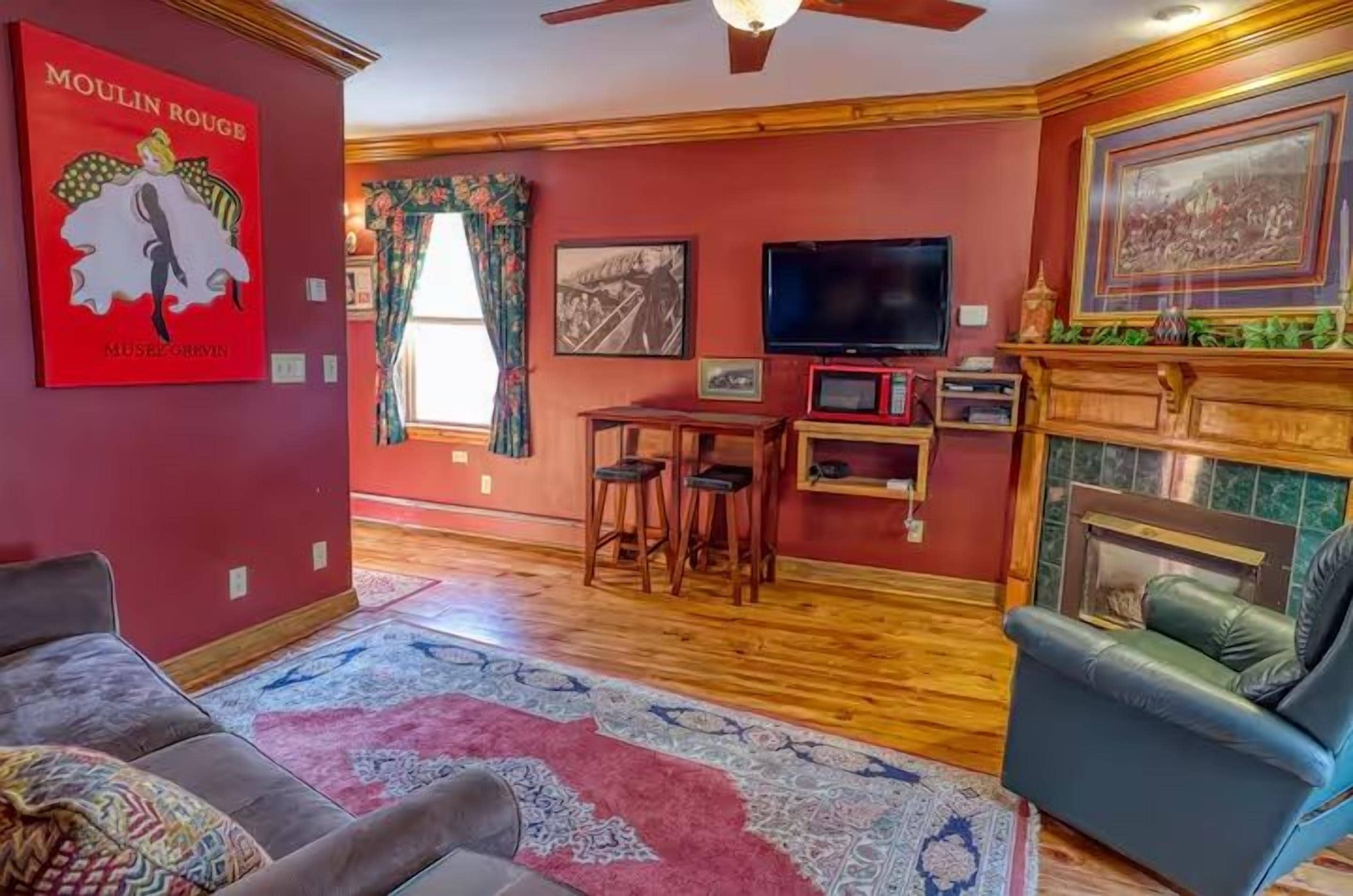 Un salon avec une cheminée, un téléviseur et un mur rouge.