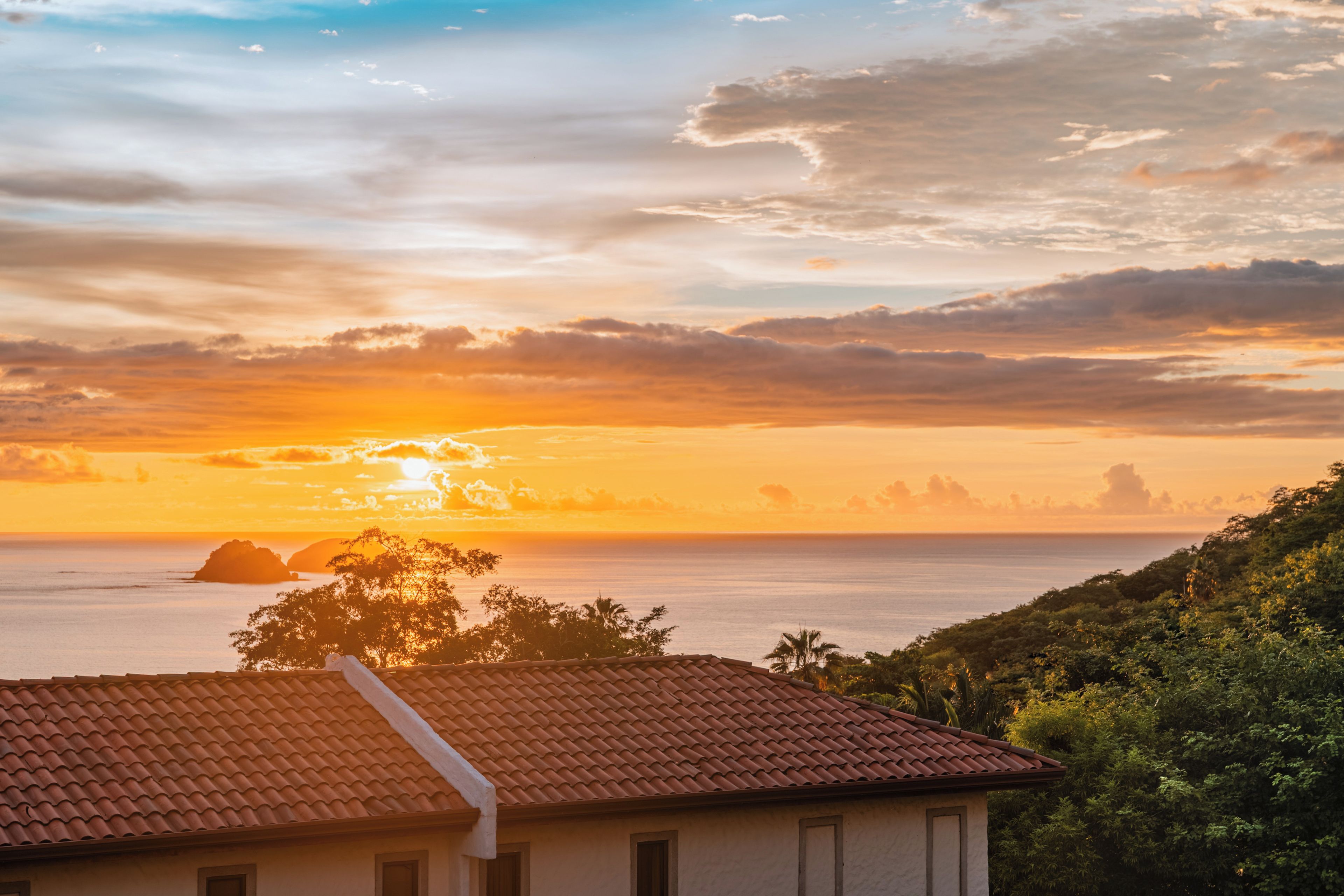 A coastal view with a house featuring a tiled roof and a view of the sea.