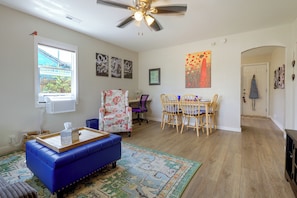 A living room with a blue sofa, a dining area with a wooden table and chairs, and a ceiling fan. - Near Bent's Old Fort: Quiet La Junta Home (La Junta)