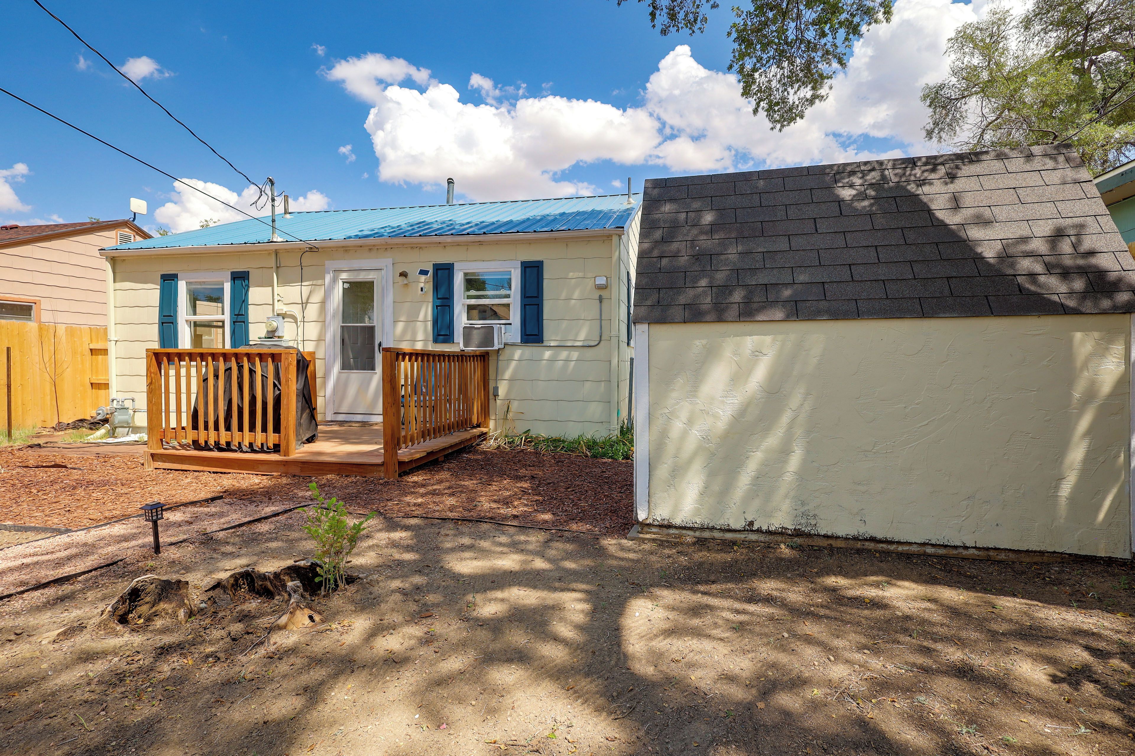 A residential property with a small house, a fenced yard, and a shed.