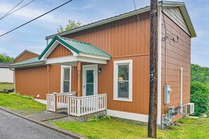 A two-story wooden house with a front porch, a garage, and a utility box.