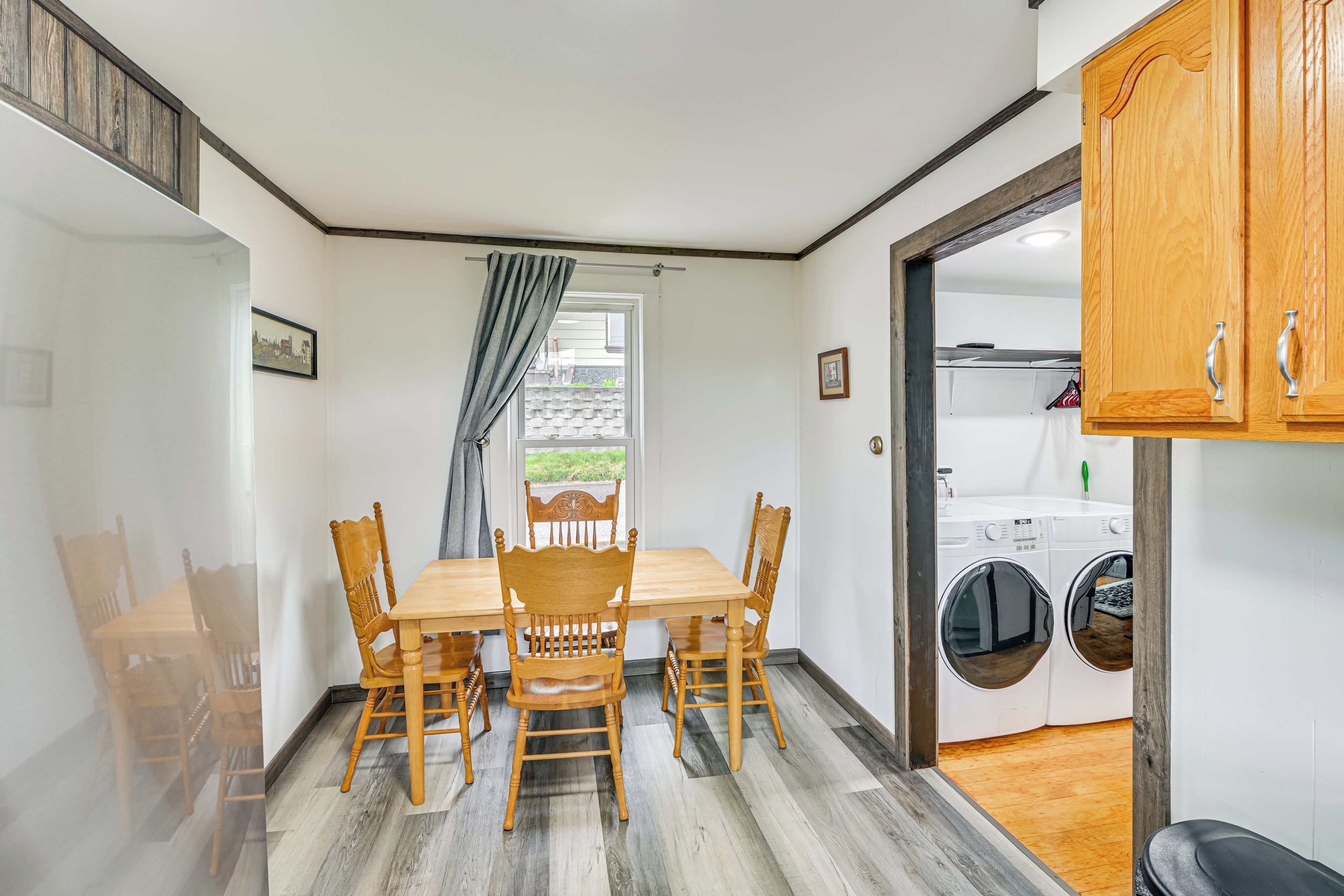 A dining area with a wooden table and chairs, a window with a view, and a laundry room with washing machines.