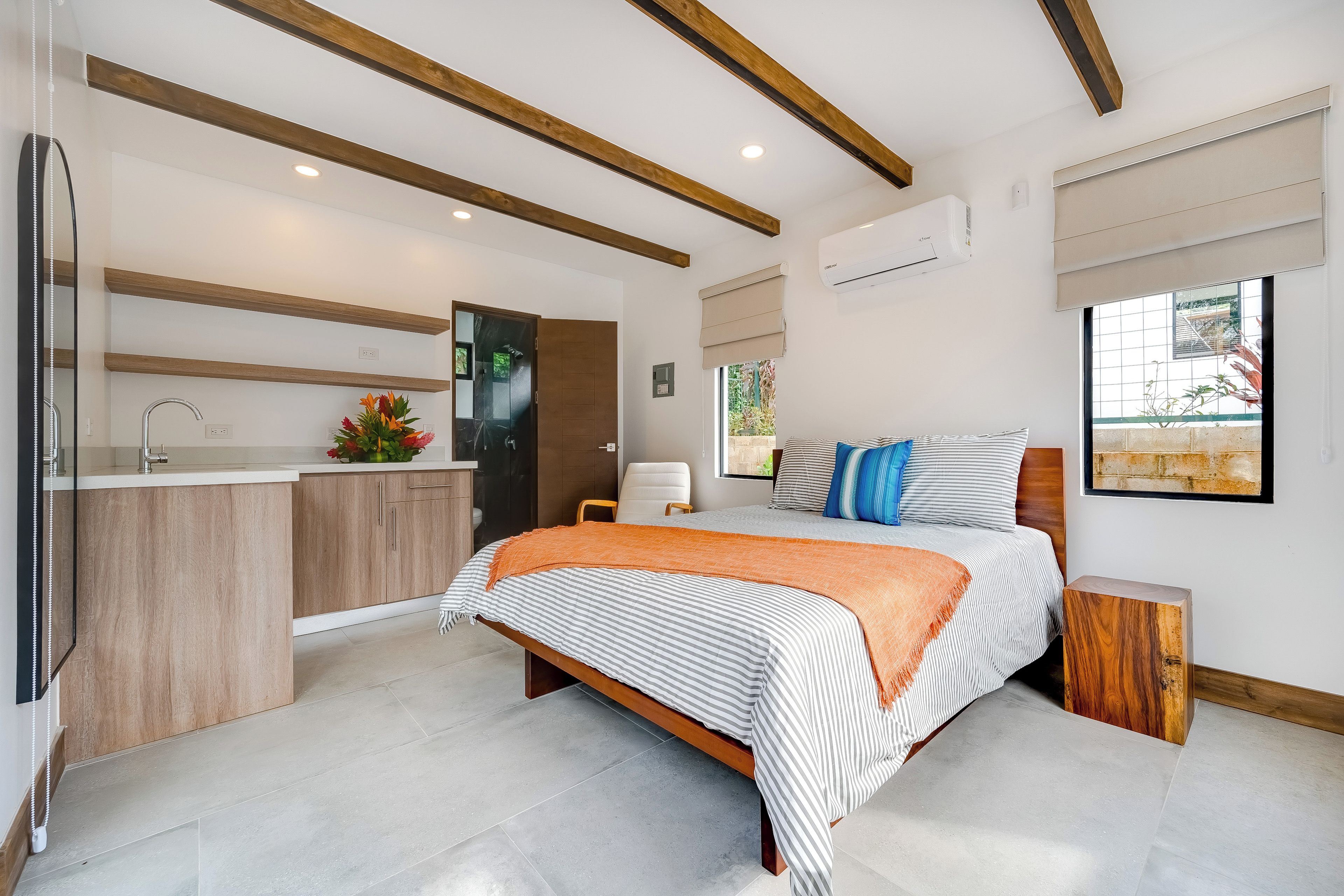 Un dormitorio moderno con una cama grande, una mesita de noche, un espejo y una ventana con vistas.