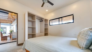 Una camera da letto con un letto, un armadio, una ventola a soffitto e una finestra.