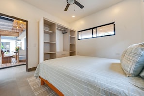 A bedroom with a bed, a wardrobe, a ceiling fan, and a window.