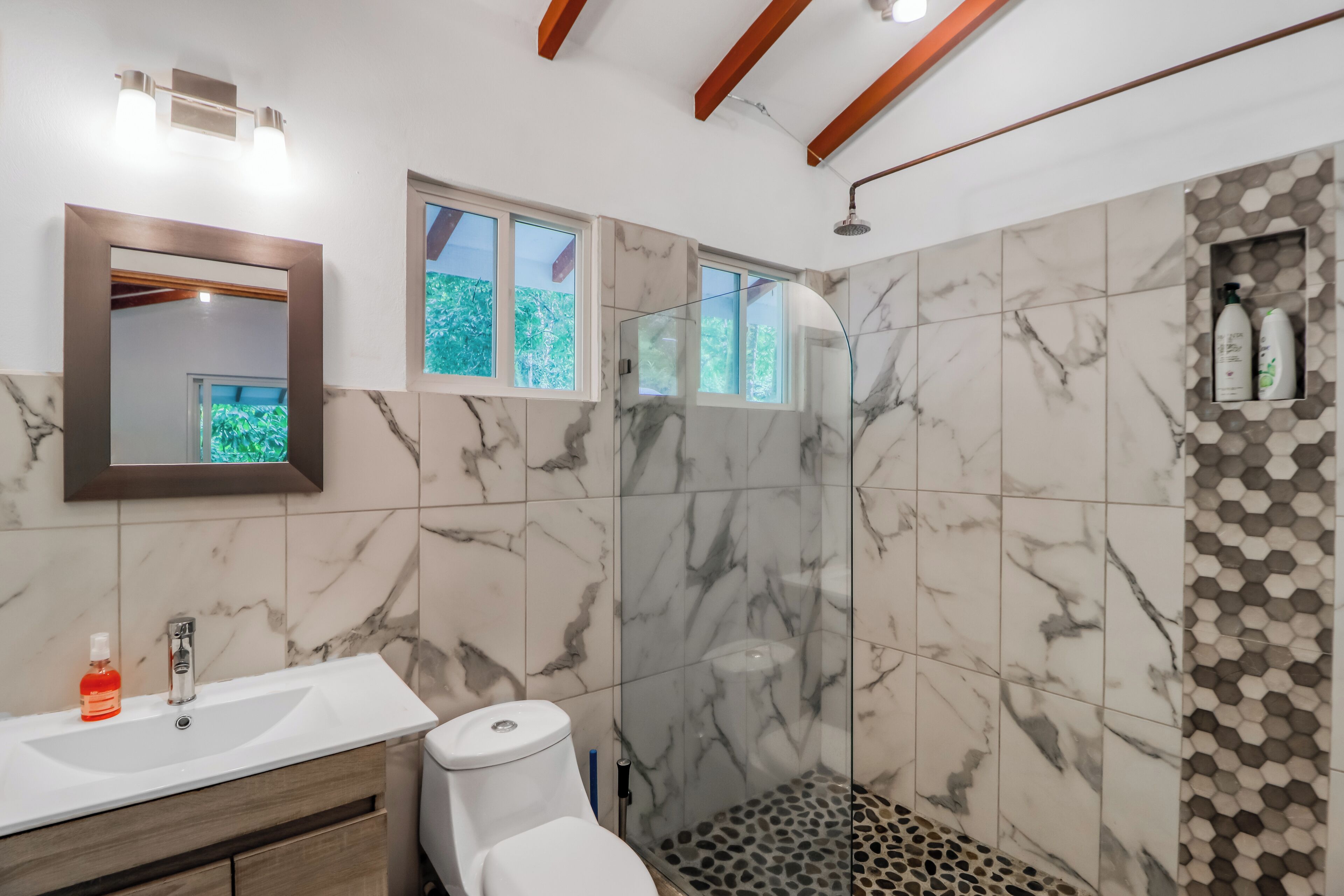 A bathroom with a white sink, a toilet, and a shower area with a glass door.