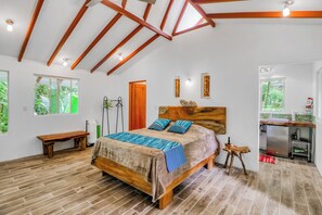 A bedroom with a wooden bed, a bench, a wooden headboard, and a view of the outdoors through a window.