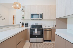 Une cuisine moderne dotée d’appareils électroménagers en acier inoxydable, de meubles en bois et d’un plan de travail blanc.