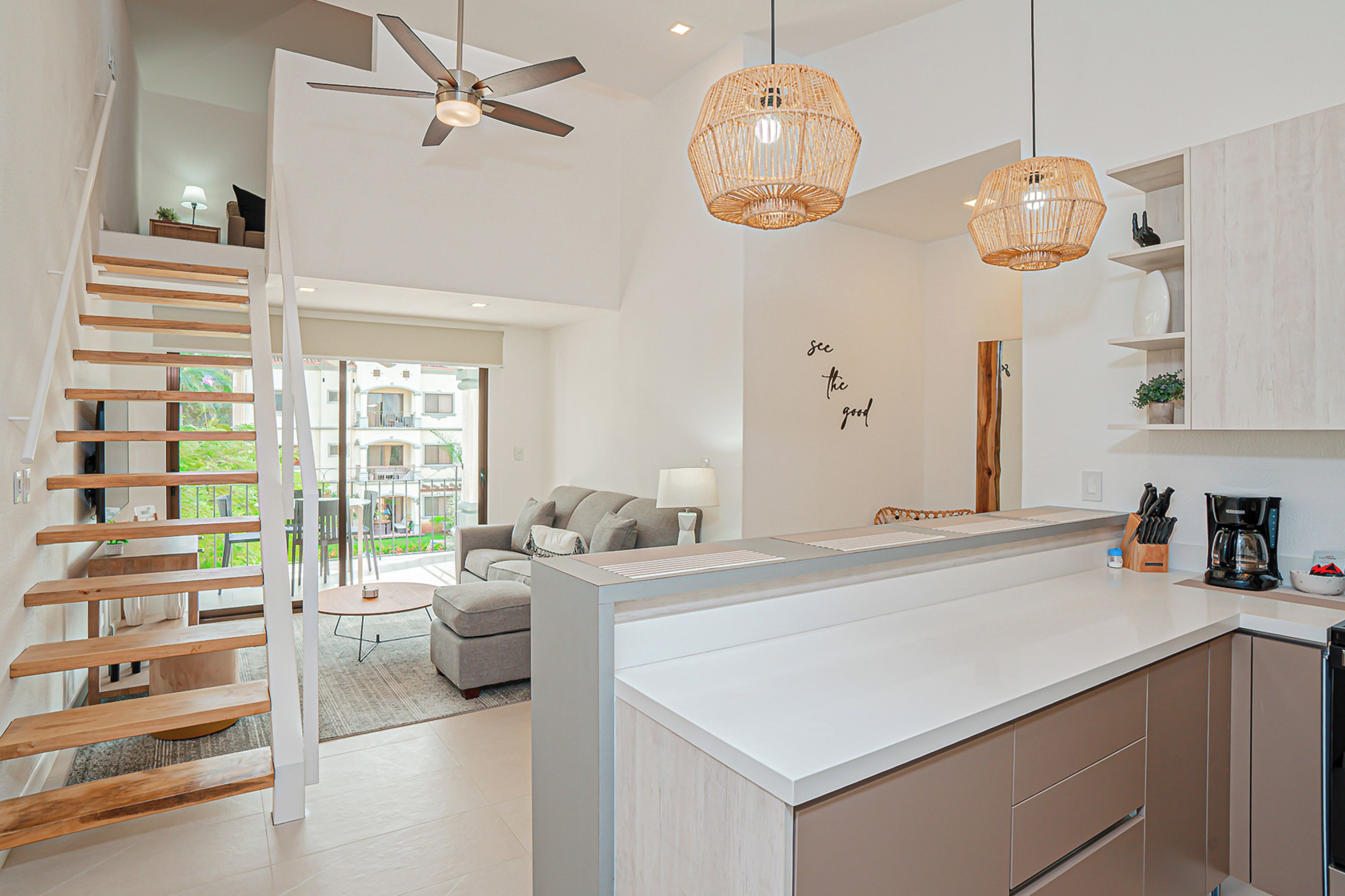 Une cuisine moderne dotée d’un îlot central, d’un escalier en bois et d’un ventilateur de plafond.