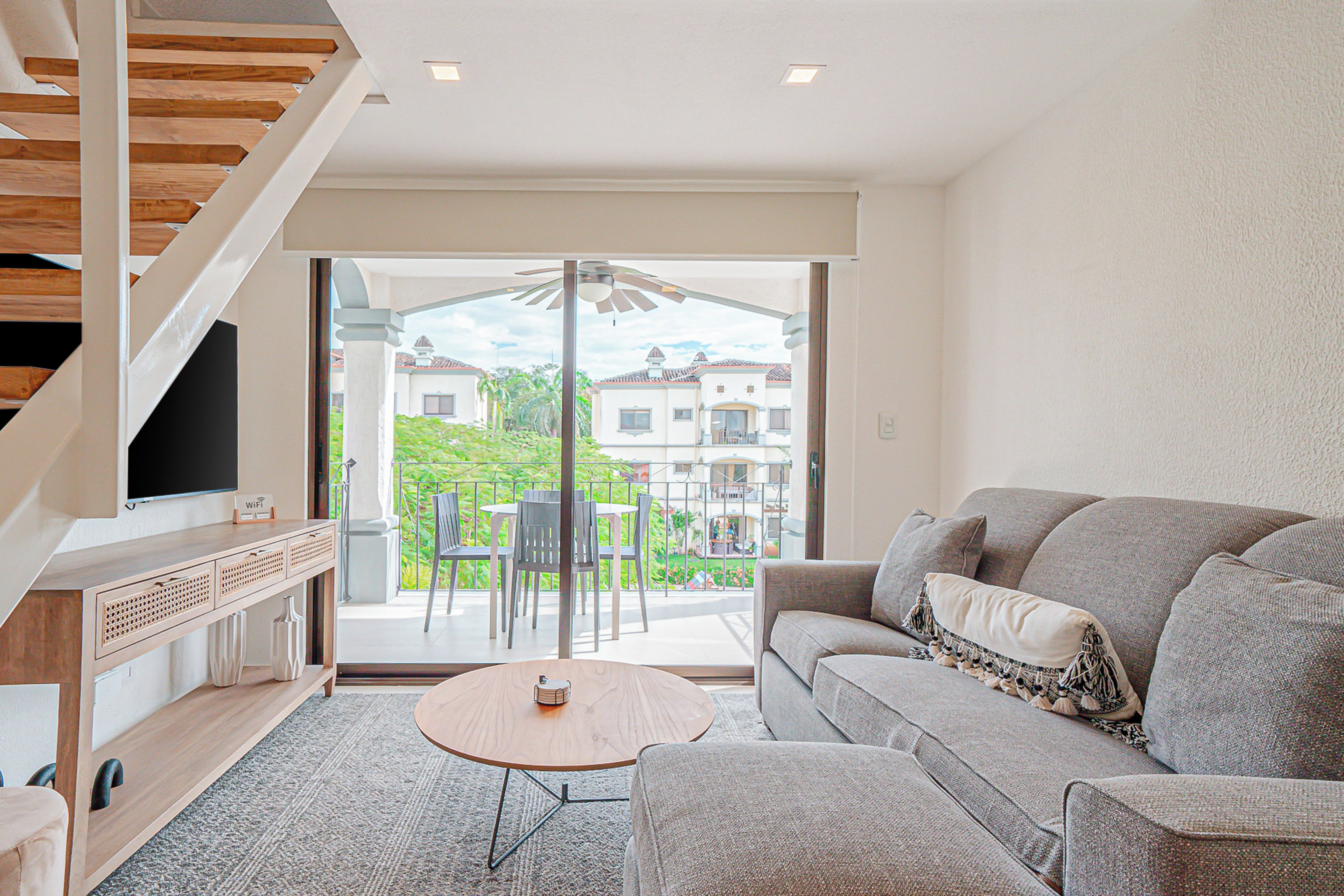 A modern living room with a sofa, coffee table, and a TV on a wooden cabinet.