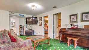 A living room with a sofa, a coffee table, a television, a bookshelf, and a piano. - Hot Tub Ski Home: Rooster's Den in Ellicottville (Ellicottville)