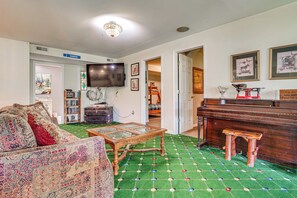 A living room with a sofa, a coffee table, a television, a bookshelf, and a piano. - Hot Tub Ski Home: Rooster's Den in Ellicottville (Ellicottville)