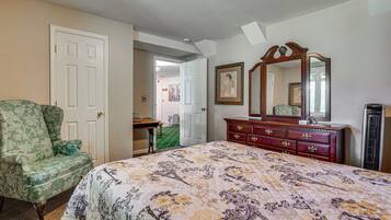 Un dormitorio con cama, cómoda, silla y una puerta que da a otra habitación.
