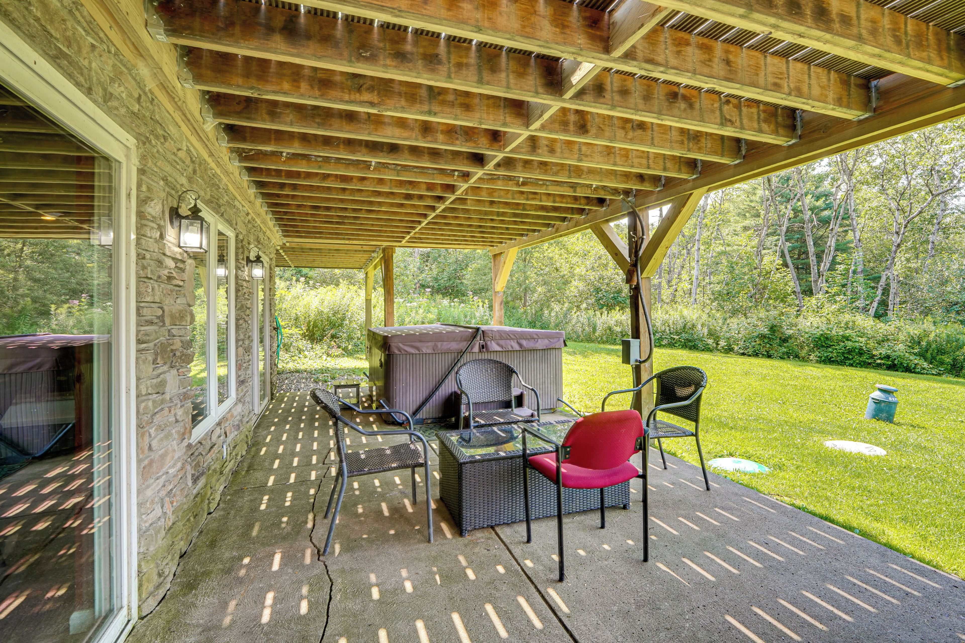 Eine Terrasse im Freien mit überdachter Sitzgruppe, Steinmauern und Blick auf einen üppigen Garten.