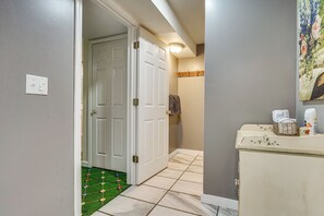 Corredor com porta branca, interruptor de luz e chão de azulejos.