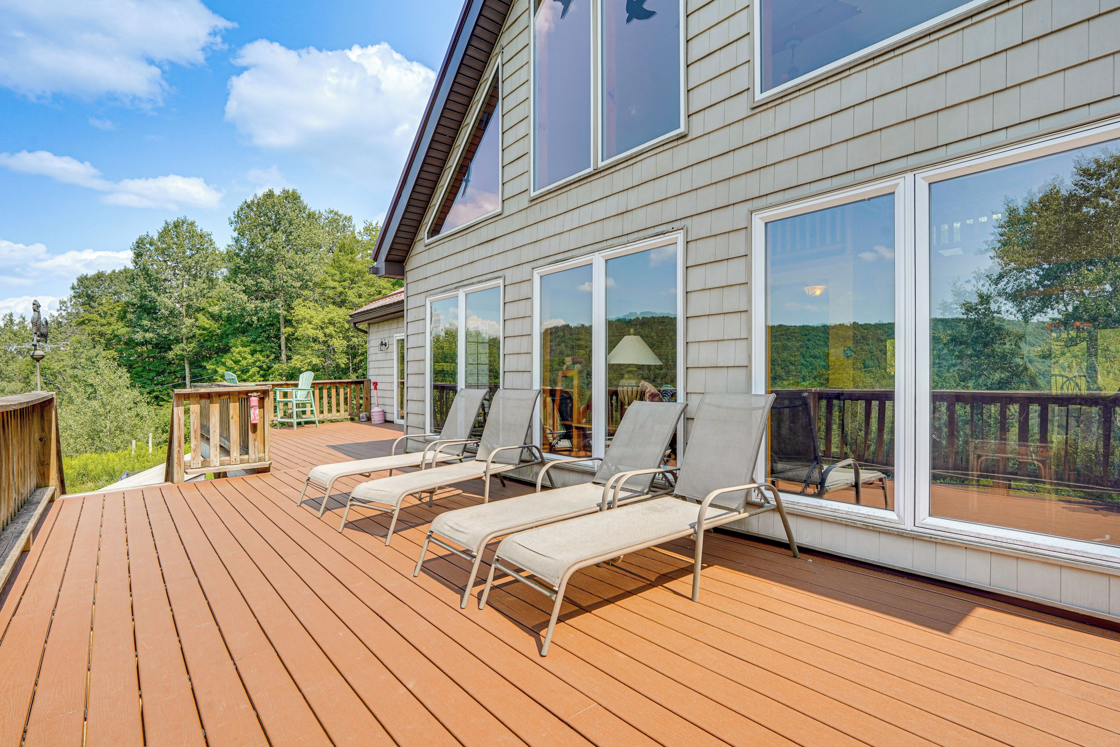 A deck with sun loungers and a view of a forested area.