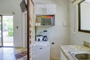 A compact kitchenette with a microwave, a blender, and a small refrigerator.
