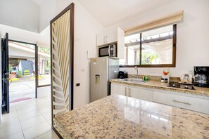 A kitchen with a granite countertop, a microwave, a refrigerator, and a window with a view of the outdoors. - 3-unit Bundle: Club Voca Pool Access, Near Beach! (Sardinal)