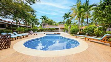 Una piscina con sillones de playa y palmeras.