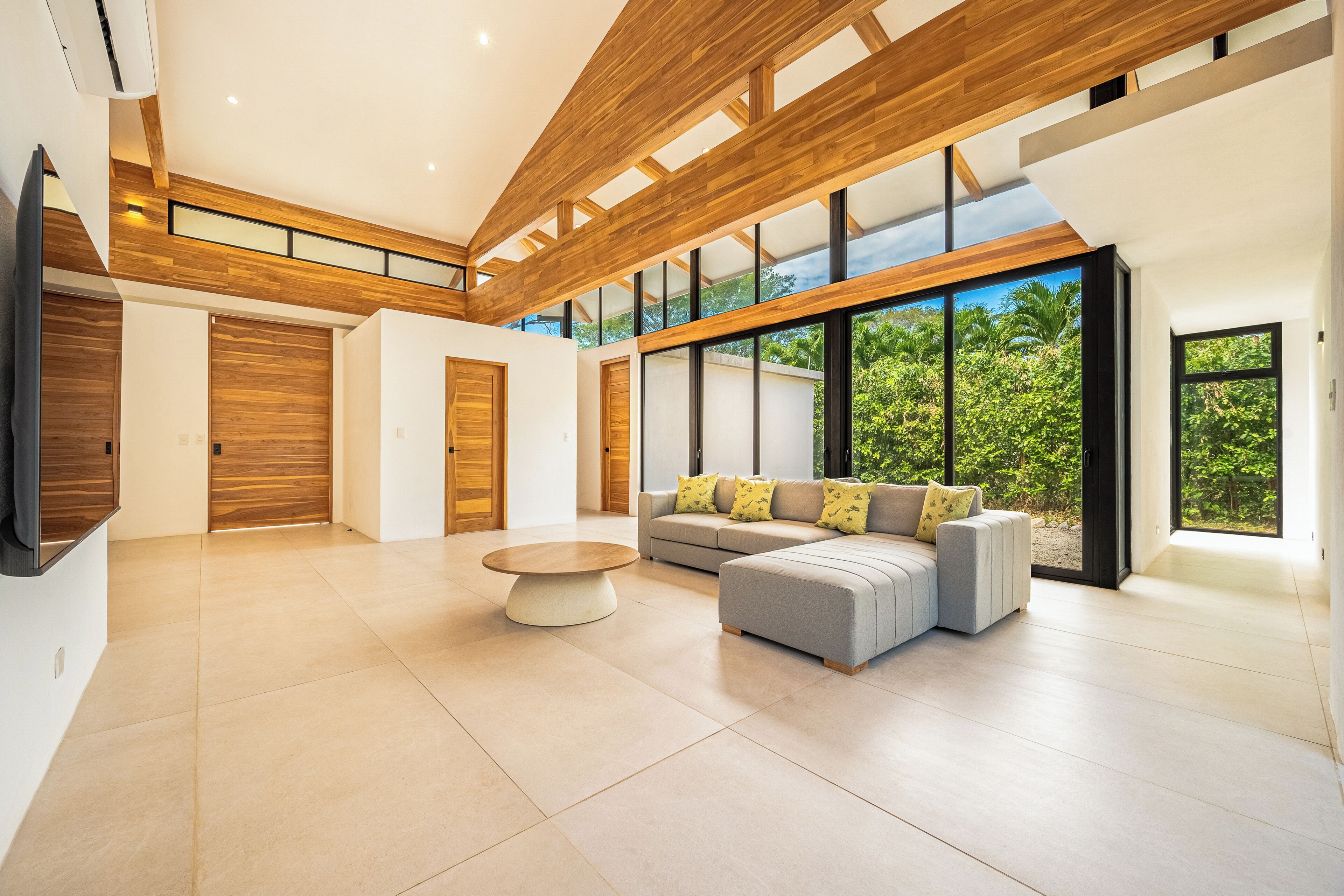 A spacious living area with a modern design, featuring a large window, a sofa set, and a coffee table.