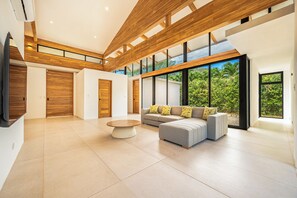 Een ruime woonkamer met een modern design, met een groot raam, een zithoek en een salontafel.