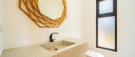A bathroom with a large, geometric mirror, a sink with a modern faucet, and a toilet.