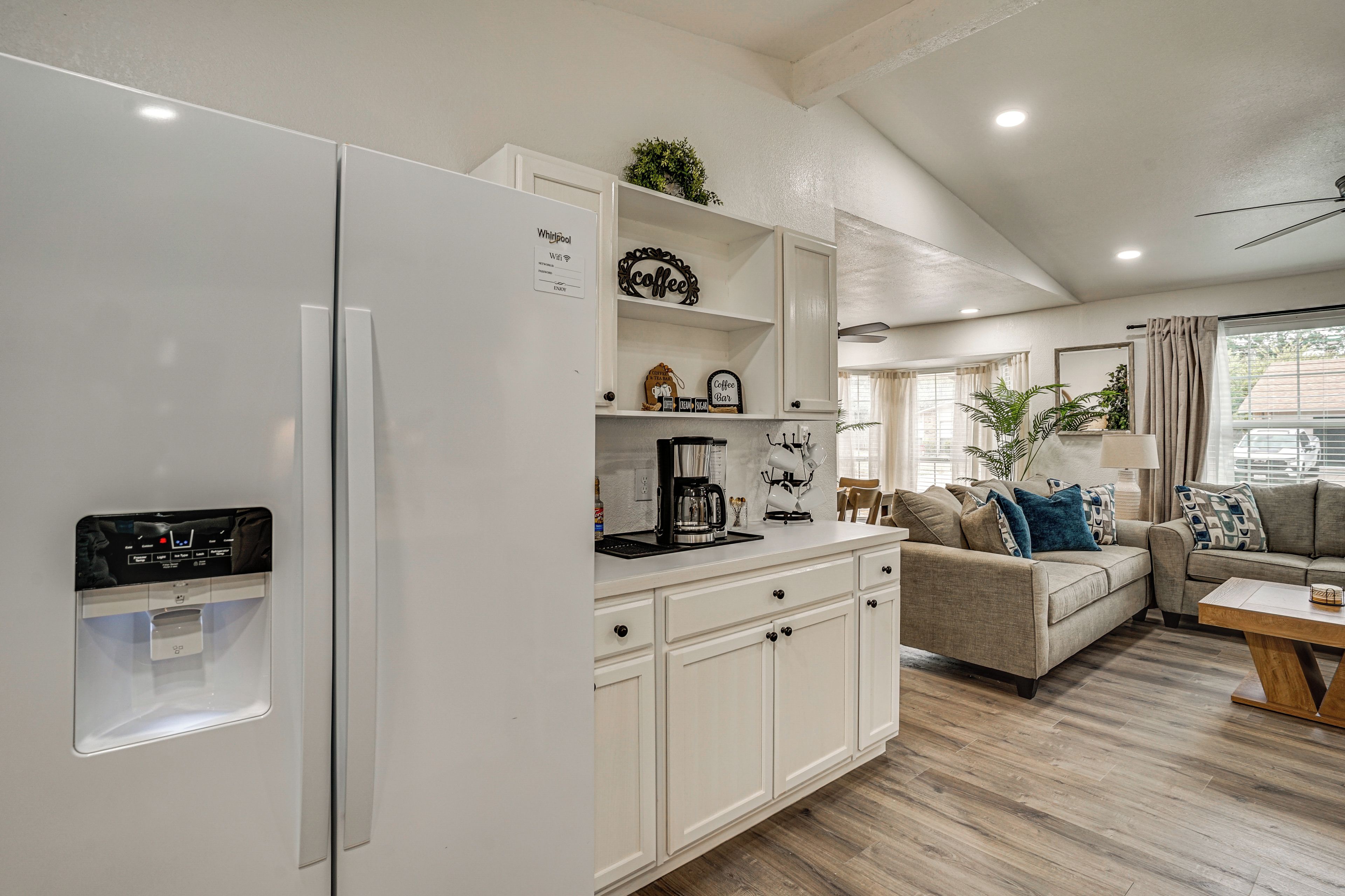 A modern kitchen with white cabinetry, a built-in refrigerator, and a coffee station.