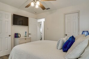 A bedroom with a bed, a dresser, a mirror, and a ceiling fan. - Explore Arlington! Centrally Located Extended Stay (Arlington)