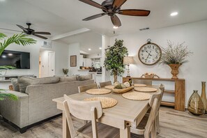 A modern living room with a sofa, dining table, and ceiling fans. - Explore Arlington! Centrally Located Extended Stay (Arlington)