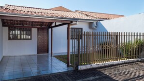 A residential building with a tiled roof, a gated entrance, and a paved driveway.
