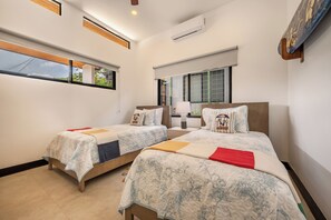 A hotel room with two beds, a window with a view, an air conditioning unit, and a ceiling fan. - Modern Tamarindo Villa Private Pool & Garden (Tamarindo)