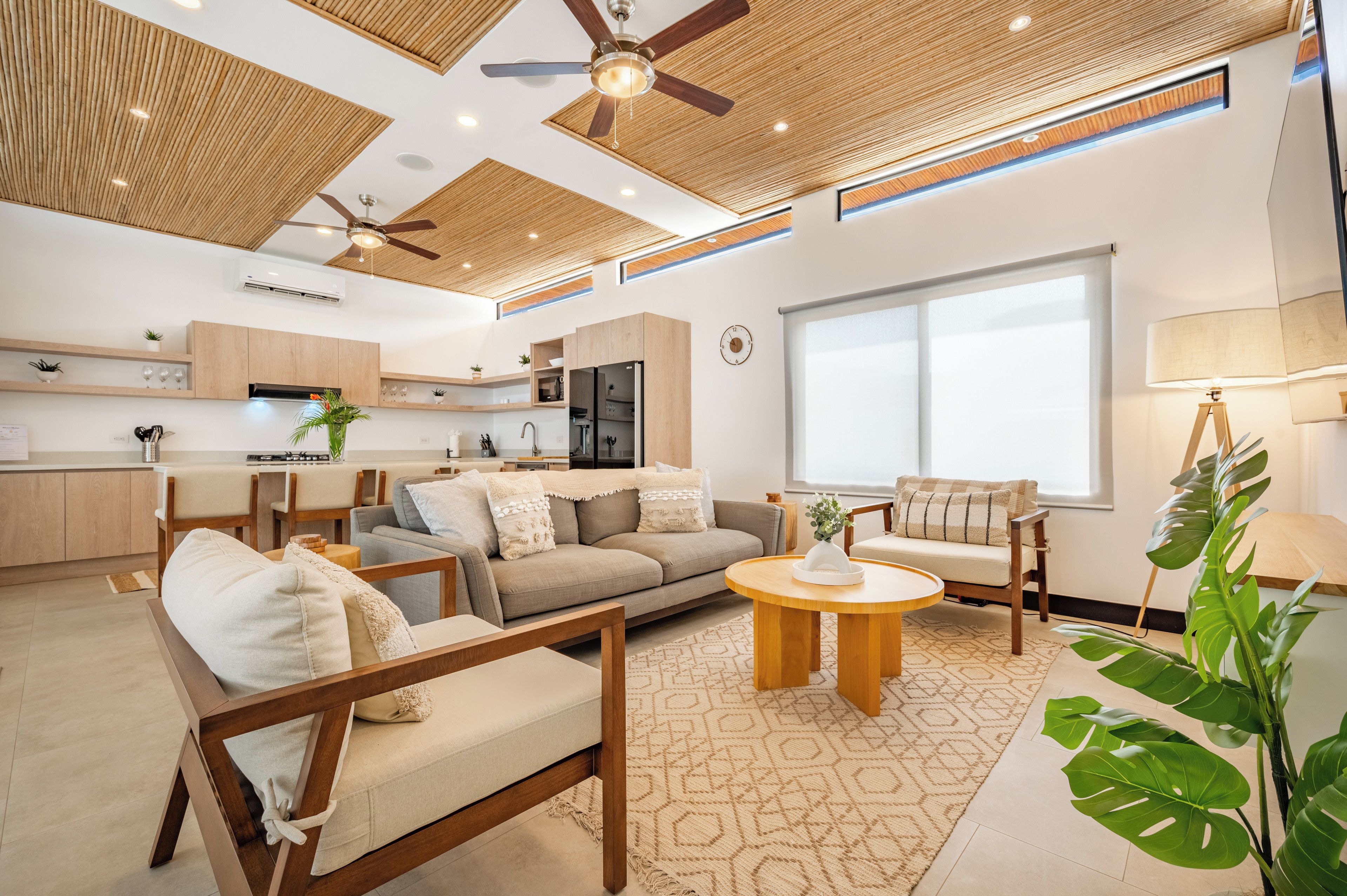A modern living room with a sofa, chairs, a coffee table, and a large window.