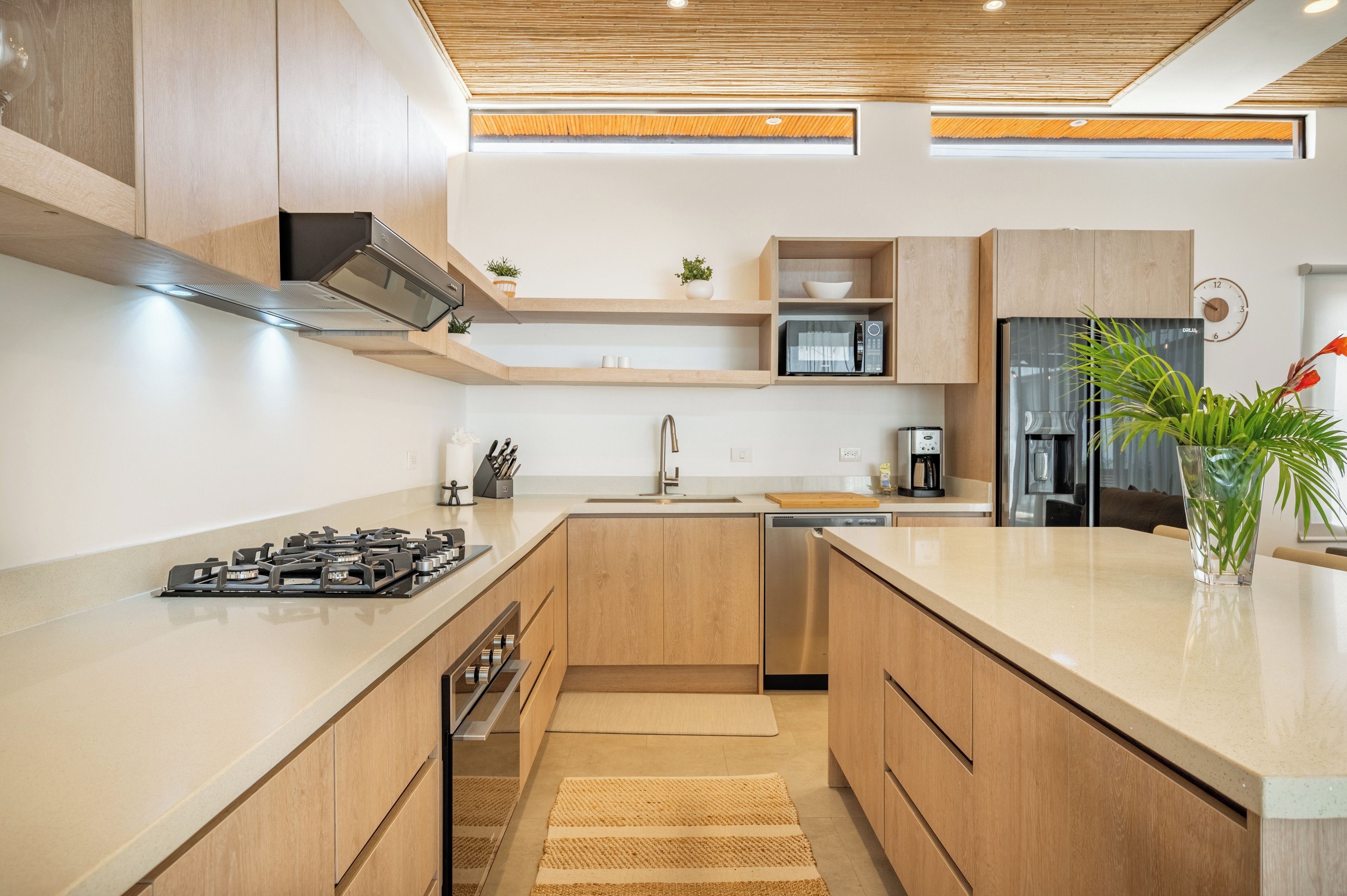 Une cuisine moderne avec des meubles en bois, une cuisinière à gaz, un four à micro-ondes, un réfrigérateur et un évier.