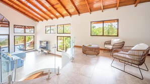 A spacious living area with a high ceiling, large windows, and a pool view. - Luxe Ocean-view Hideaway in Carrillo (Puerto Carrillo)